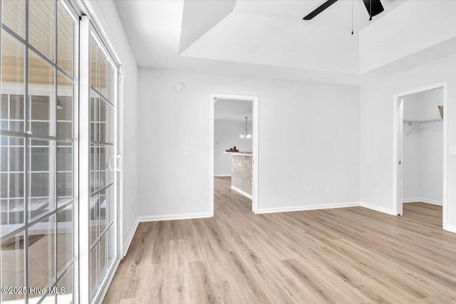 unfurnished bedroom with a closet, baseboards, a walk in closet, and wood finished floors