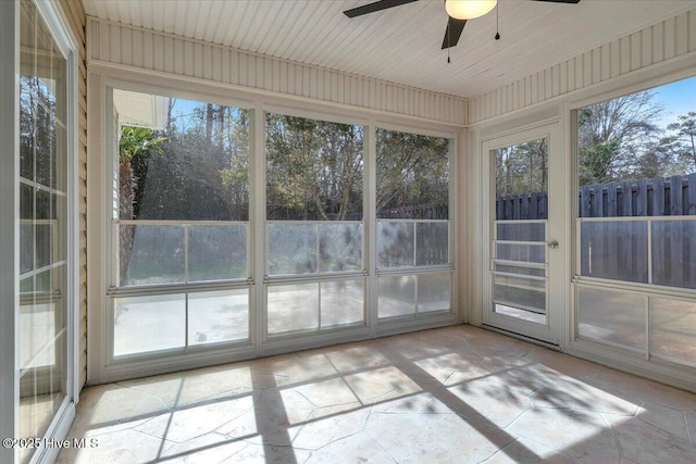 unfurnished sunroom featuring a ceiling fan and a healthy amount of sunlight