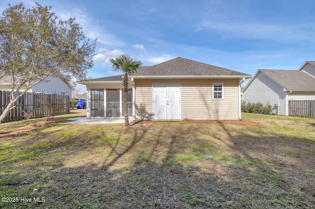 back of house featuring a shingled roof, a sunroom, a lawn, and fence