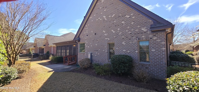 view of property exterior with fence, a patio, and brick siding