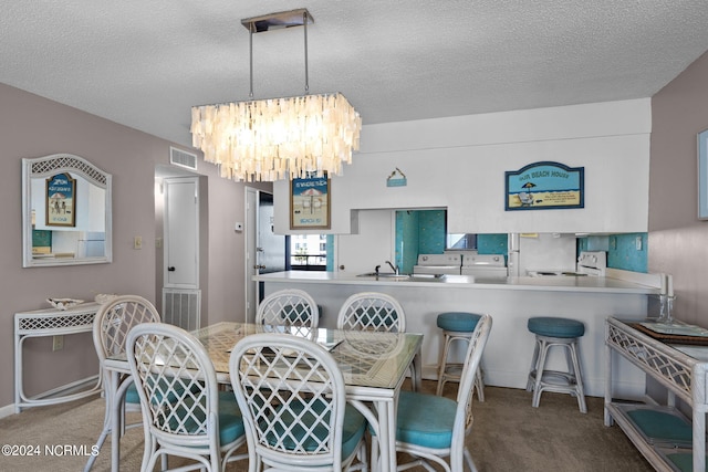 carpeted dining space with washer / dryer, visible vents, a notable chandelier, and a textured ceiling