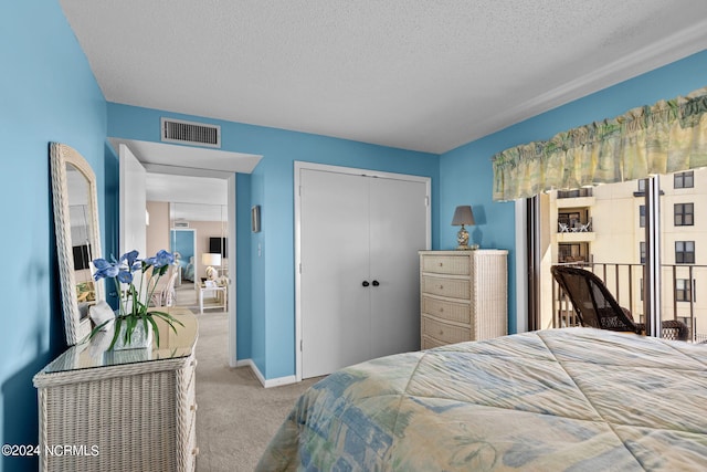 carpeted bedroom with a textured ceiling, a closet, visible vents, and baseboards