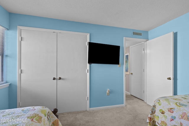 bedroom featuring a closet, visible vents, carpet flooring, a textured ceiling, and baseboards