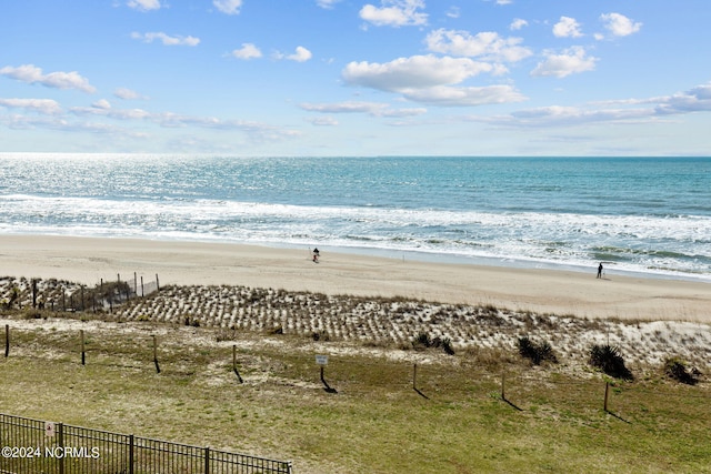 view of water feature featuring fence and a view of the beach