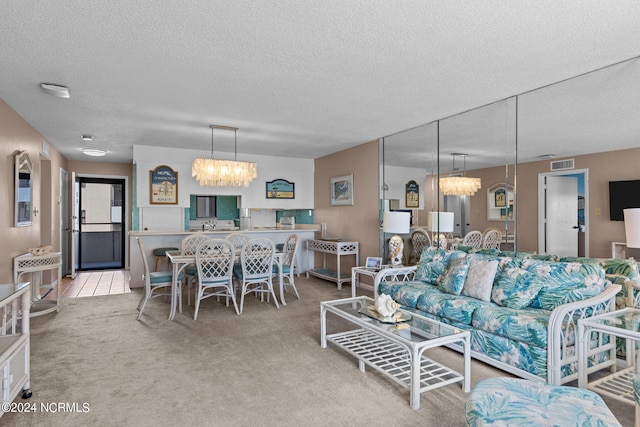 living room featuring a chandelier, carpet floors, a textured ceiling, and visible vents