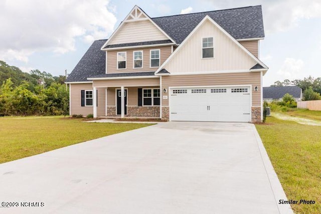 craftsman house with driveway, stone siding, covered porch, and a front yard