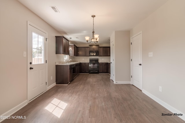 kitchen with dark brown cabinetry, baseboards, wood finished floors, an inviting chandelier, and black appliances