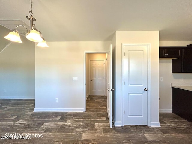 interior space featuring dark wood-style floors, decorative light fixtures, dark brown cabinetry, and baseboards