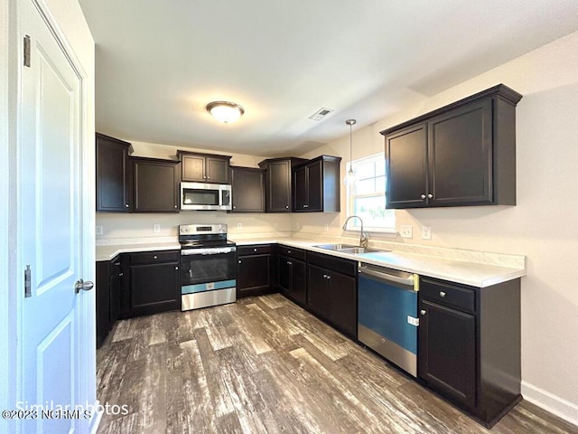 kitchen with stainless steel appliances, dark wood-type flooring, a sink, and light countertops