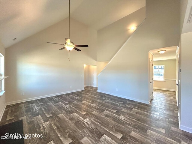 unfurnished room featuring dark wood-type flooring, high vaulted ceiling, and baseboards