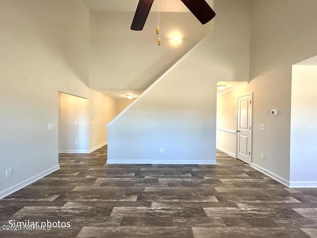 spare room with high vaulted ceiling, wood finished floors, a ceiling fan, and baseboards