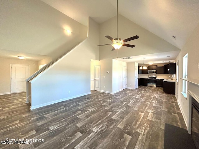 unfurnished living room featuring stairs, baseboards, dark wood-type flooring, and a sink