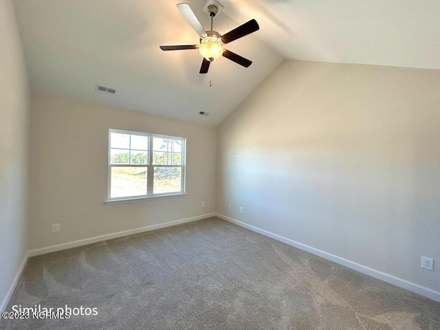 empty room featuring lofted ceiling, carpet floors, visible vents, and baseboards