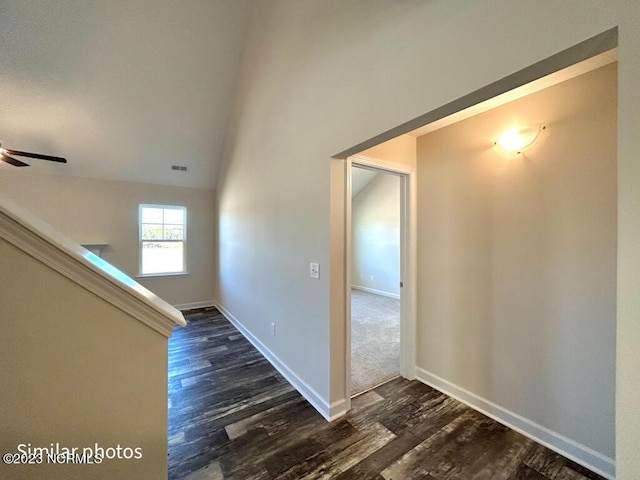 hall with lofted ceiling, dark wood-style flooring, visible vents, and baseboards