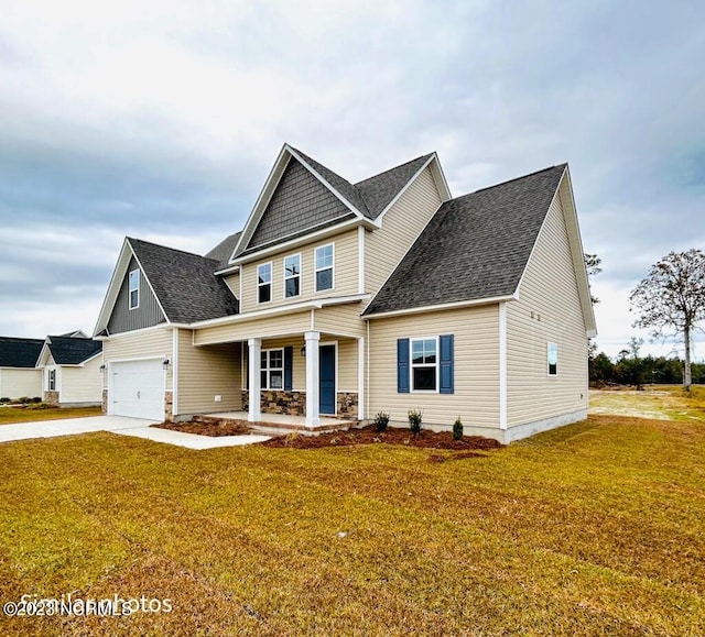 craftsman-style home featuring a shingled roof, covered porch, driveway, and a front lawn