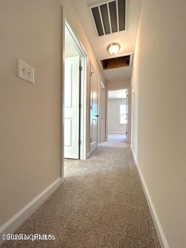 corridor featuring carpet, visible vents, and baseboards