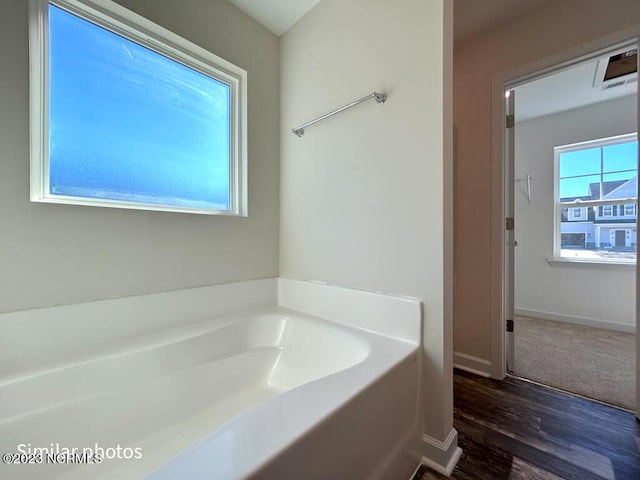 bathroom with wood finished floors, a garden tub, and baseboards