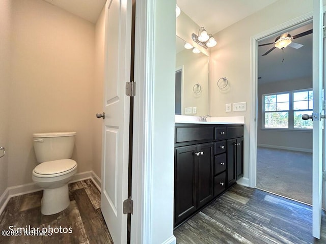 bathroom featuring toilet, a ceiling fan, vanity, wood finished floors, and baseboards