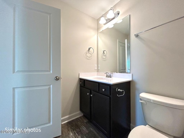 bathroom featuring toilet, baseboards, wood finished floors, and vanity