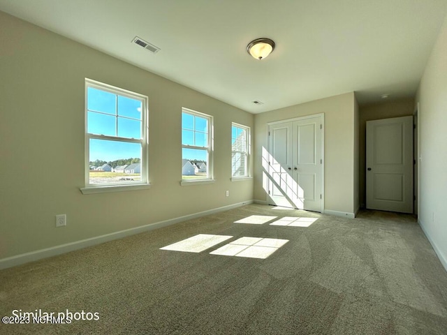 unfurnished bedroom with carpet floors, a closet, visible vents, and baseboards