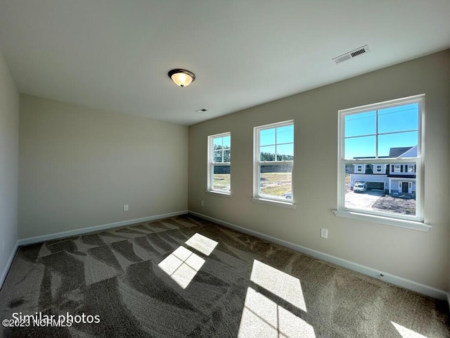 spare room with carpet floors, visible vents, and baseboards