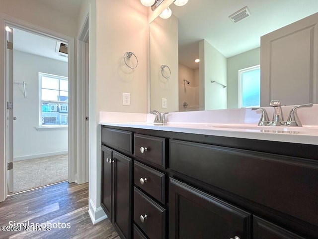 bathroom featuring double vanity, baseboards, visible vents, wood finished floors, and a sink