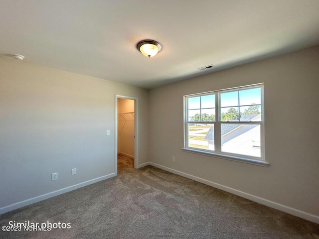 carpeted empty room featuring visible vents and baseboards