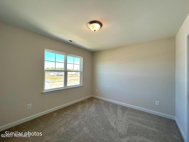 carpeted spare room with visible vents and baseboards