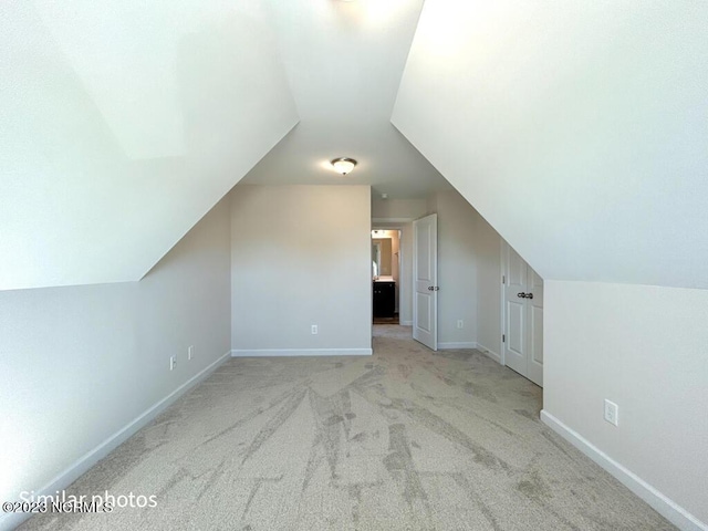 additional living space featuring carpet floors, vaulted ceiling, and baseboards