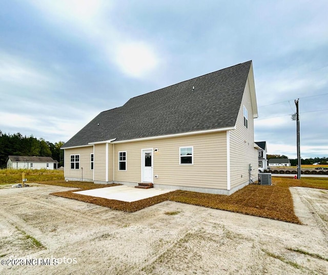 rear view of house featuring a shingled roof, cooling unit, a patio area, and entry steps