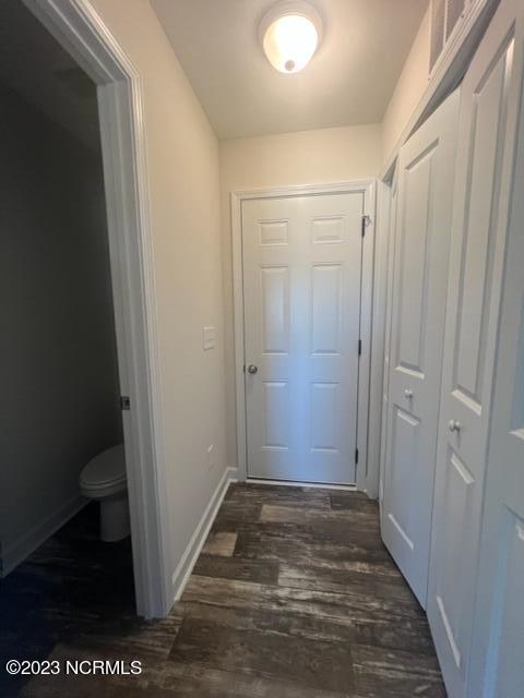 hallway featuring visible vents, baseboards, and dark wood-type flooring