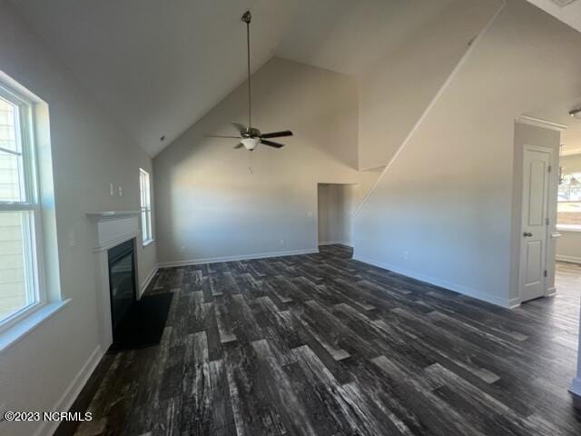 unfurnished living room featuring dark wood-style floors, a glass covered fireplace, and a healthy amount of sunlight