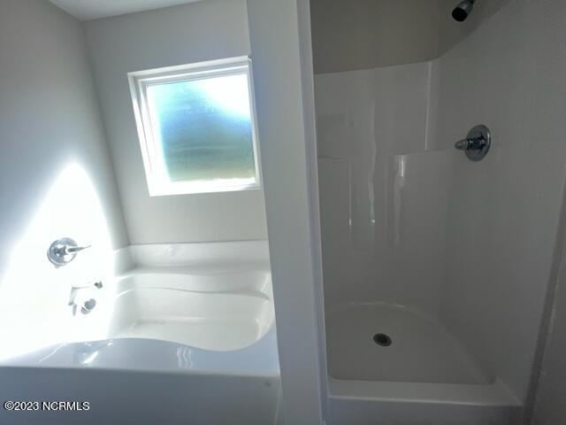 bathroom featuring a garden tub and a shower