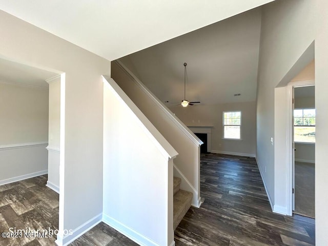 stairs featuring wood finished floors, a ceiling fan, and baseboards