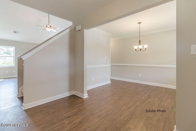 spare room featuring visible vents, ornamental molding, wood finished floors, baseboards, and ceiling fan with notable chandelier