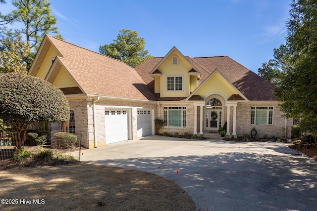 view of front of house with brick siding, a shingled roof, concrete driveway, fence, and a garage