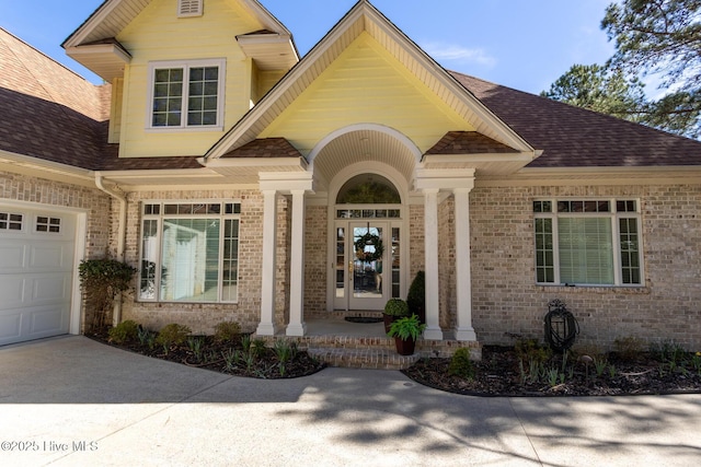 view of front facade featuring brick siding, roof with shingles, and an attached garage