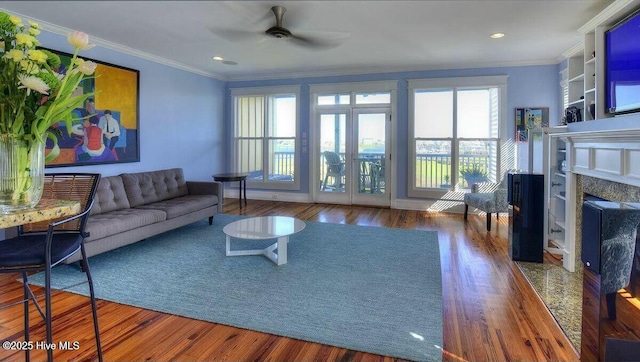 living area with ornamental molding, wood finished floors, and a high end fireplace