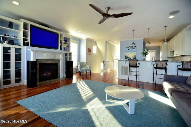 living area with ornamental molding, a high end fireplace, and wood finished floors