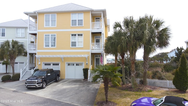 beach home with concrete driveway, an attached garage, and fence