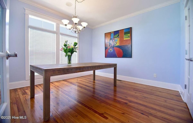 unfurnished dining area with an inviting chandelier, baseboards, crown molding, and wood finished floors