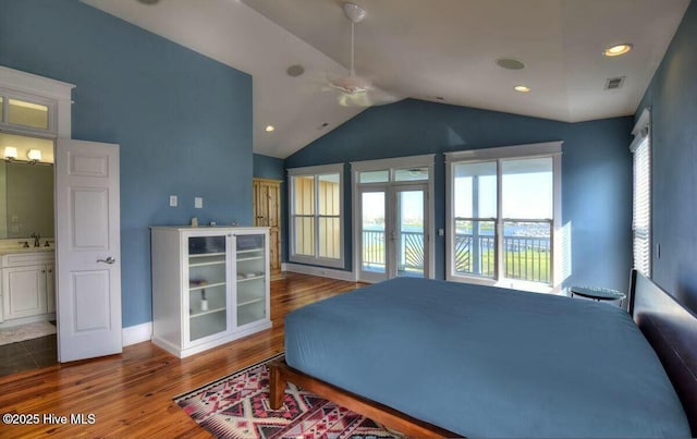 bedroom featuring visible vents, lofted ceiling, wood finished floors, access to exterior, and a sink