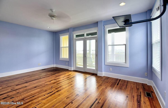 empty room with hardwood / wood-style flooring, baseboards, visible vents, and french doors