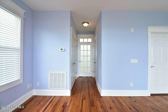 foyer entrance featuring visible vents, baseboards, and wood finished floors