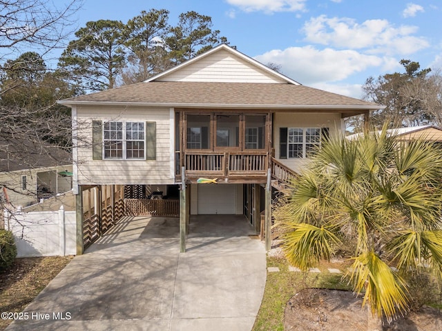 coastal inspired home featuring an attached garage, a shingled roof, a sunroom, stairs, and driveway