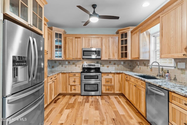 kitchen with tasteful backsplash, appliances with stainless steel finishes, light brown cabinetry, light wood-style floors, and a sink