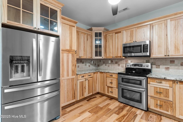 kitchen featuring visible vents, decorative backsplash, stainless steel appliances, light brown cabinetry, and light wood-type flooring