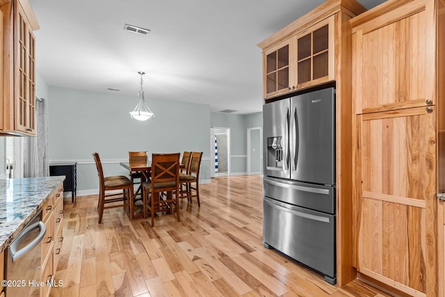 kitchen featuring appliances with stainless steel finishes, visible vents, light wood finished floors, and light stone countertops