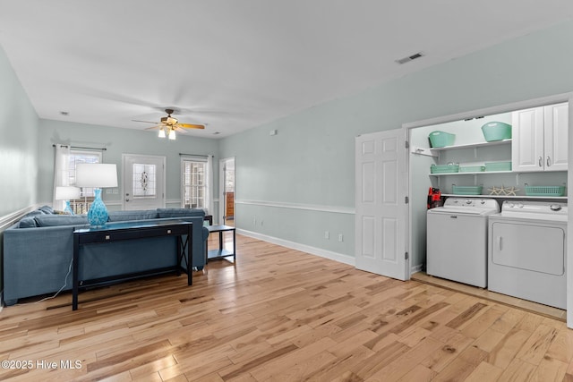 living room with light wood finished floors, visible vents, washing machine and dryer, ceiling fan, and baseboards