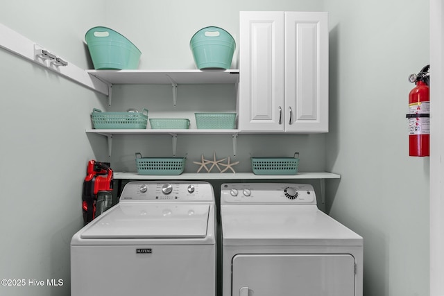 clothes washing area featuring cabinet space and washing machine and clothes dryer